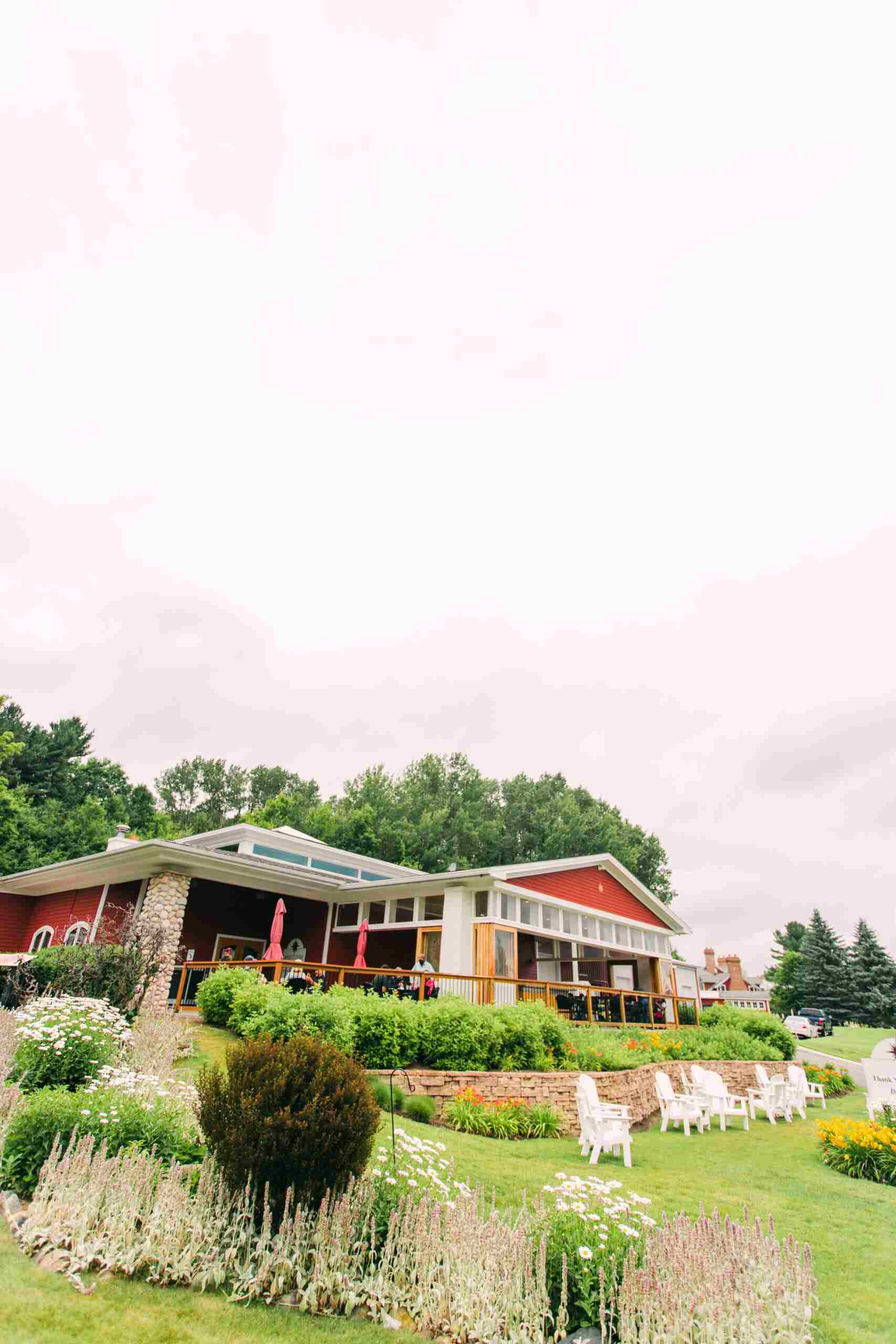 Black_Star_Farms_Winery Scenic view of a red barn surrounded by white chairs and colorful flowers.