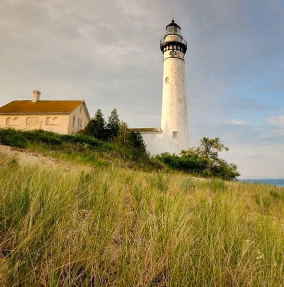 Northern Michigan Lighthouse A woman leading a horse through a grassy field.