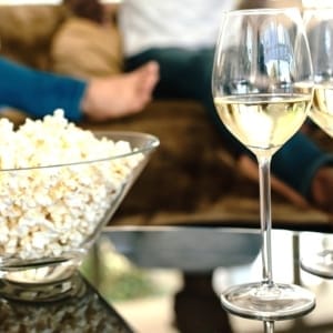 Popcorn and drinks with couple relaxing in background Winter Wine Ideas 4