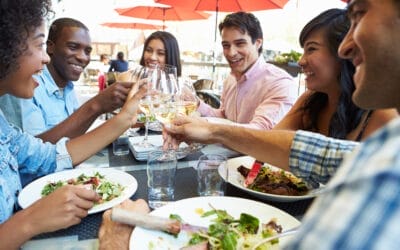 People dining and clinking glasses of white wine.