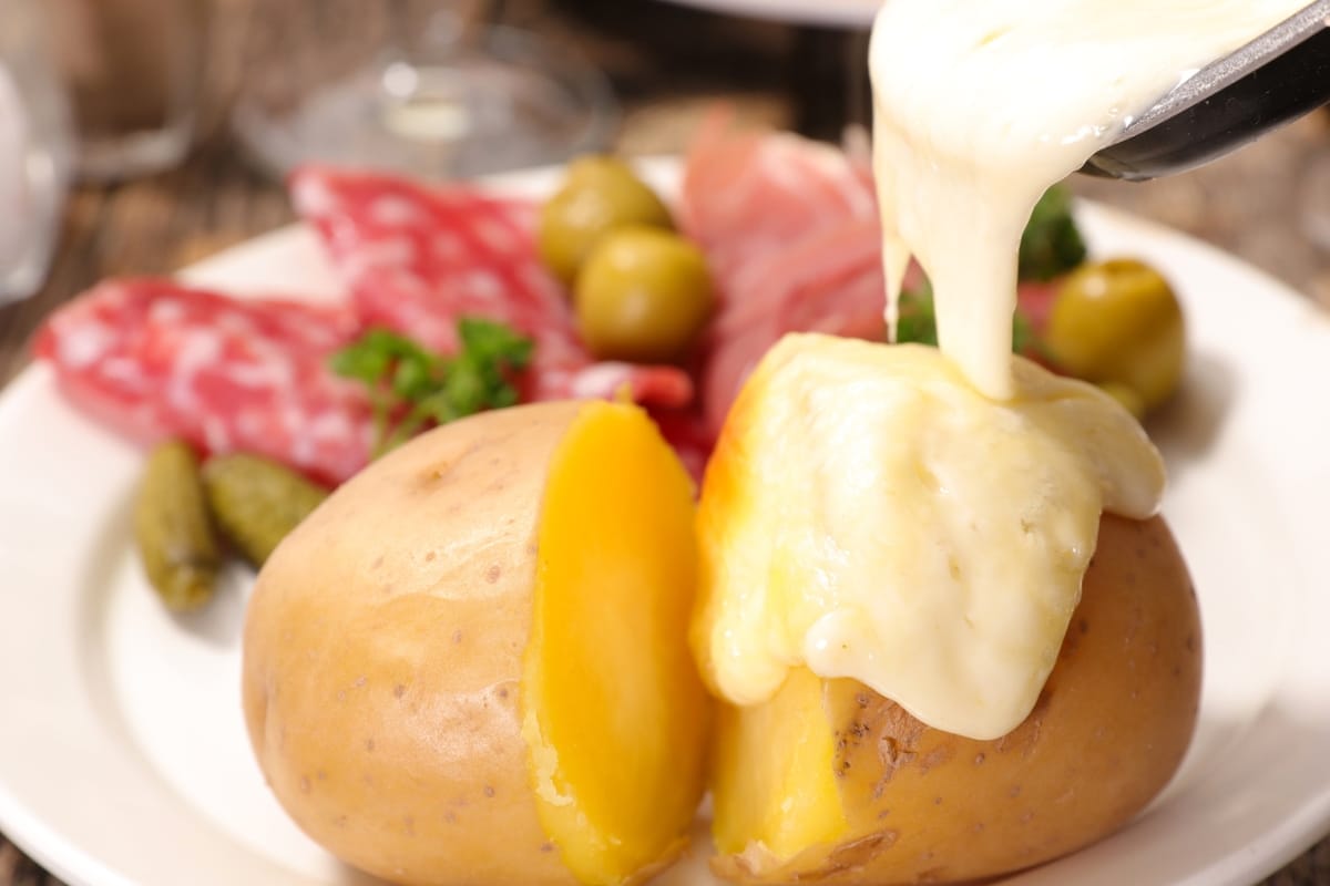 Raclette Dinners 4 Pouring melted Raclette cheese over potatoes.