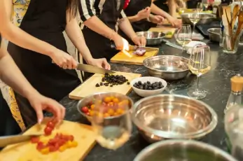 People working in a cooking class with glasses of wine