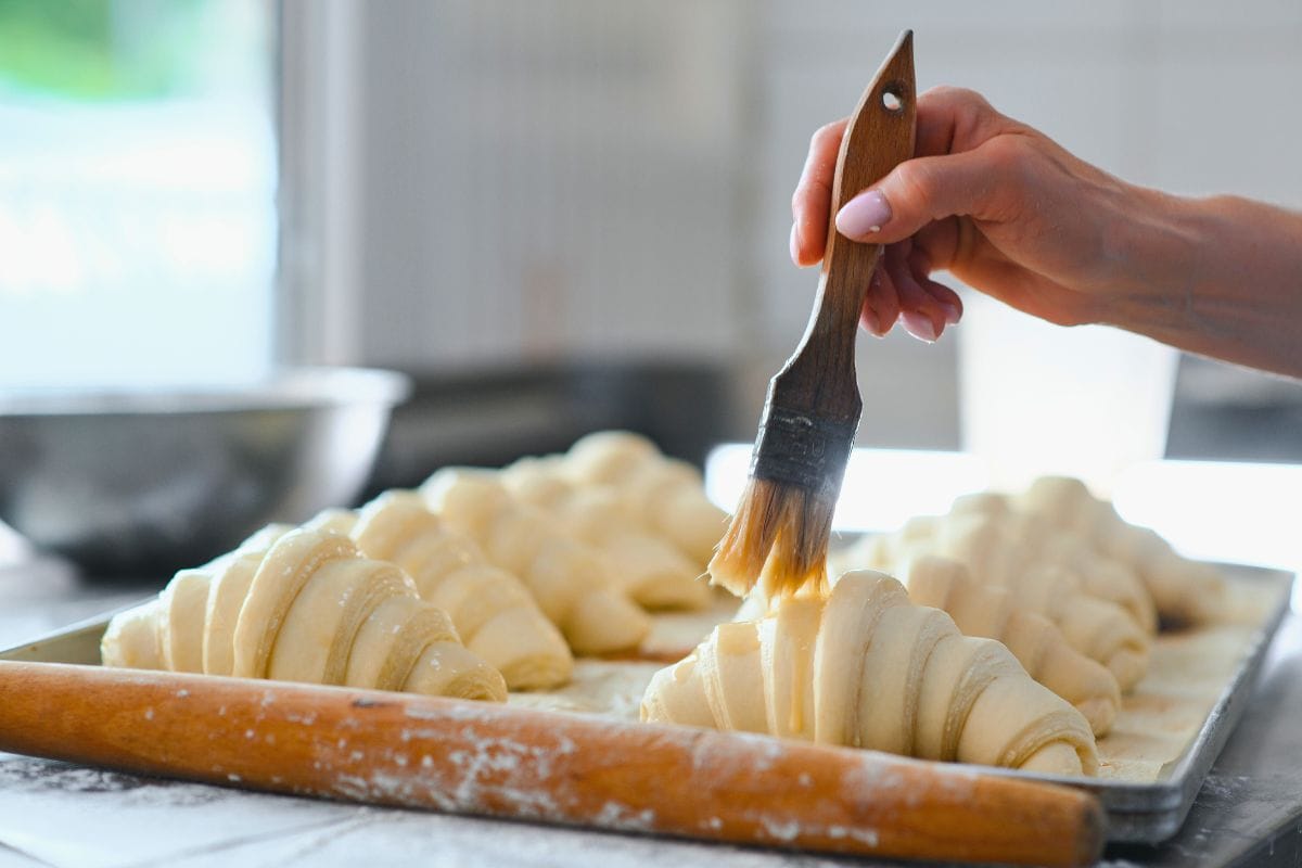 Spring School Series: Croissant Dough Class 1 Person brushing the top of prepared croissant dough
