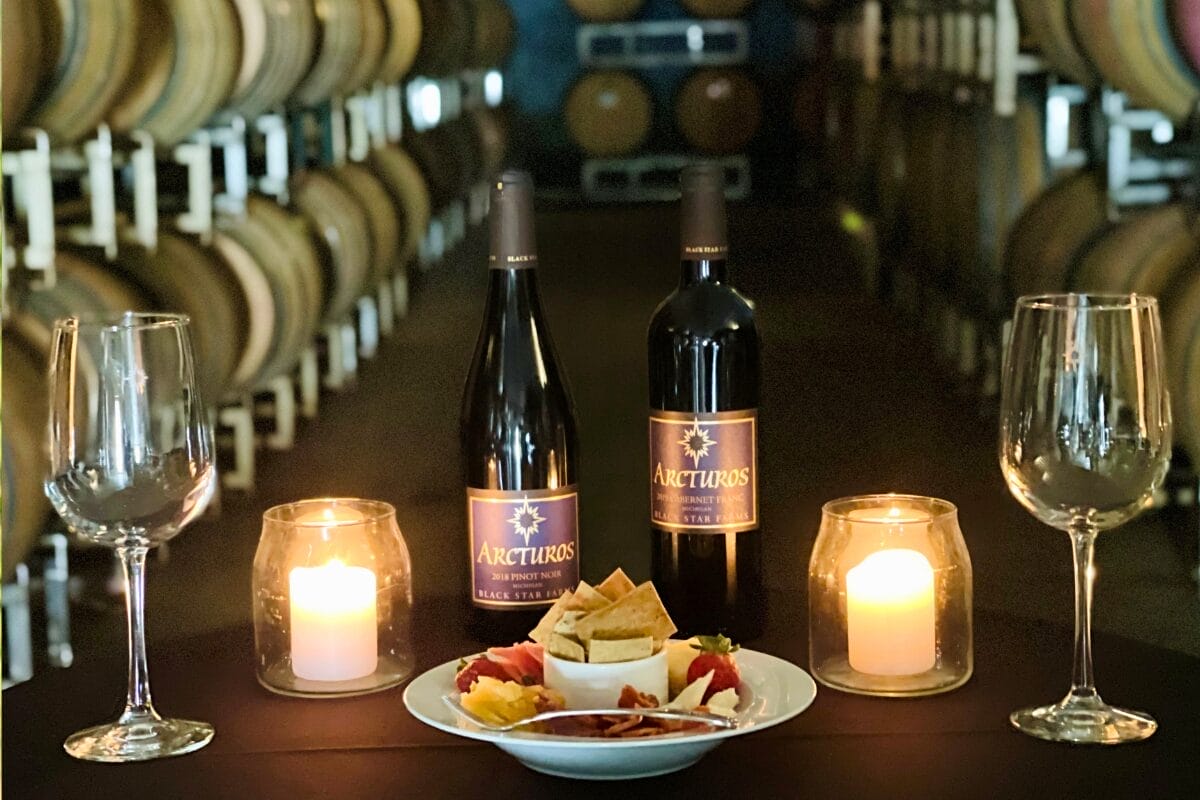Two bottles of wine with charcuterie and candles in a wine cave.